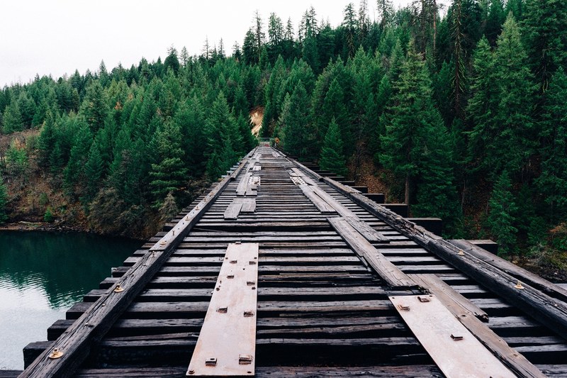 railroad track on a bridge over water near a forest, railroad over a river 4k