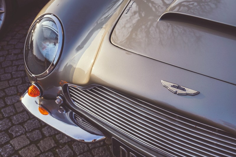gray aston martin vintage car with reflective shiny paint on a brick road, calandre daston martin 4k