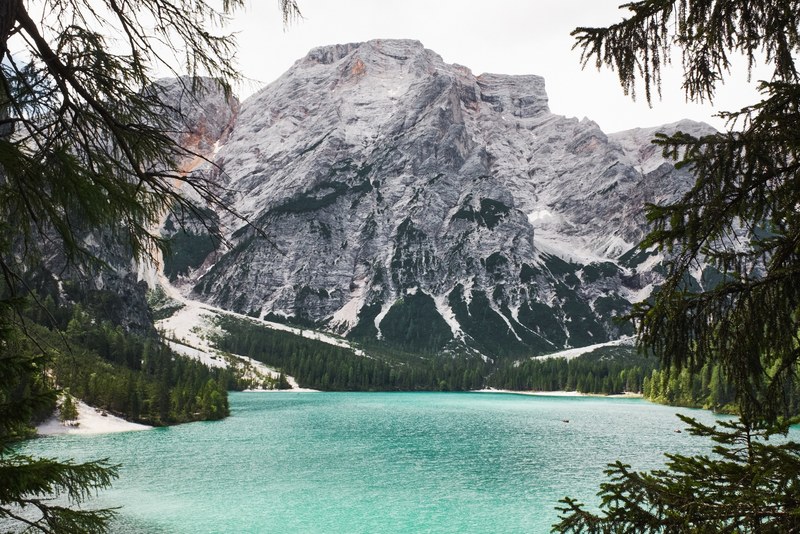 a turquoise lake at the foot of a steep mountain, mountain near lago di braies 4k