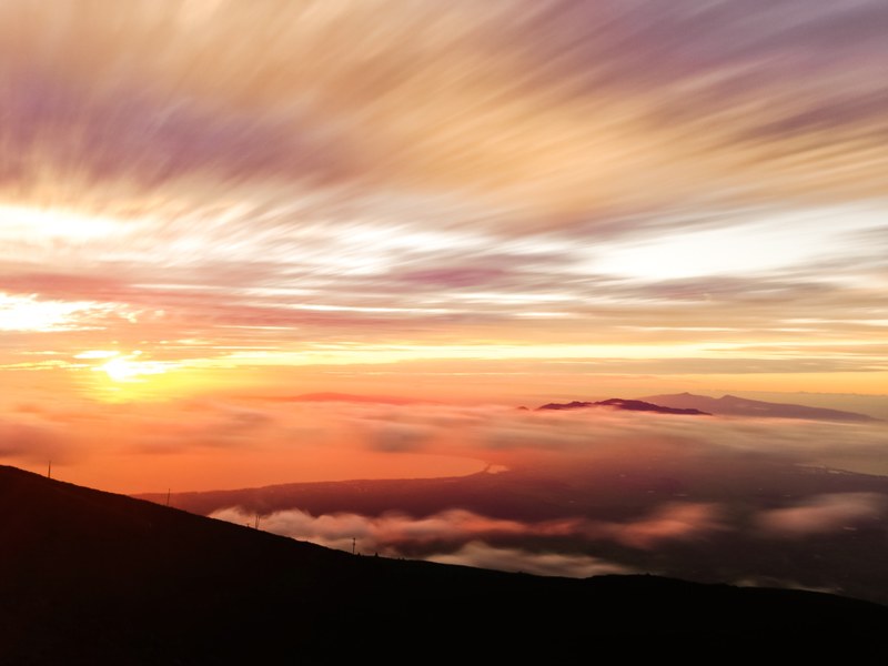 various shades of sunset cascading along sky with clouds floating below, vibrant sunset 4k