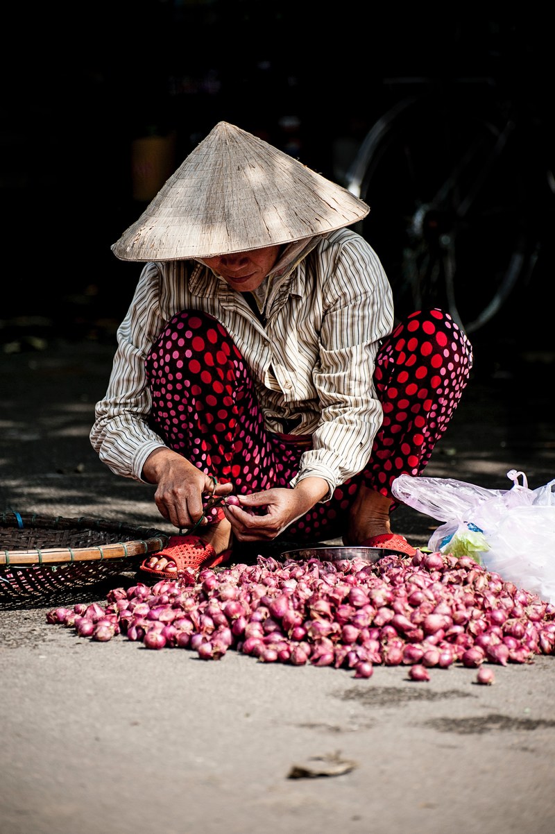 worker pares pile of fresh shallots for a vietnamese market, vietnamese farmer 4k