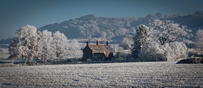 a rural house sits between two snow covered trees on a farm in shropshire uk, house in the country 4k
