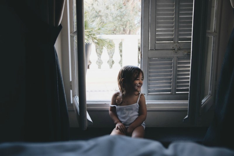 facepainted child sitting by an open window and smiling during daytime in monte carlo, baby with smile in the morning 4k