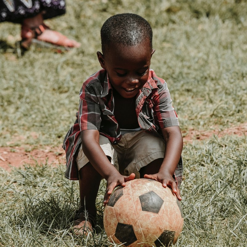 child smiling and touching the dirty soccer ball in the field with hands, child smiling with a soccer ball 4k