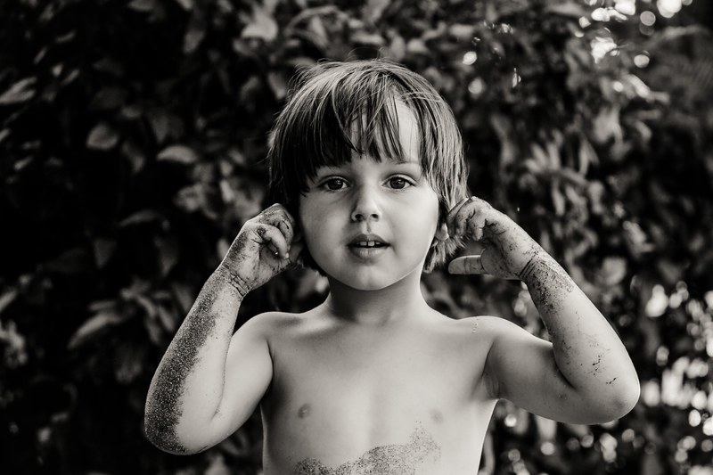 black and white shot of young boy with long hair covered in mud costa rica, young boy covered in mud 4k