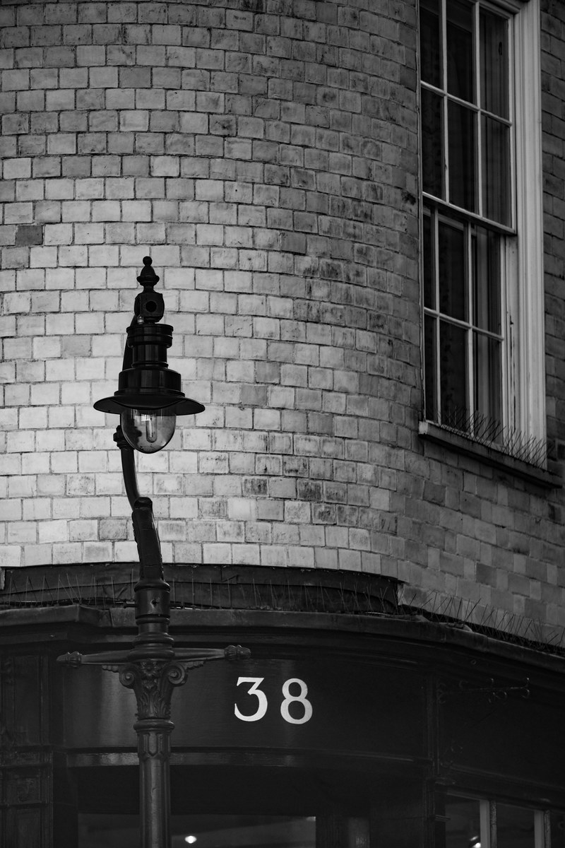 black and white shot of traditional street light near brick building with number 38 sign, number 38 and streetlight 4k