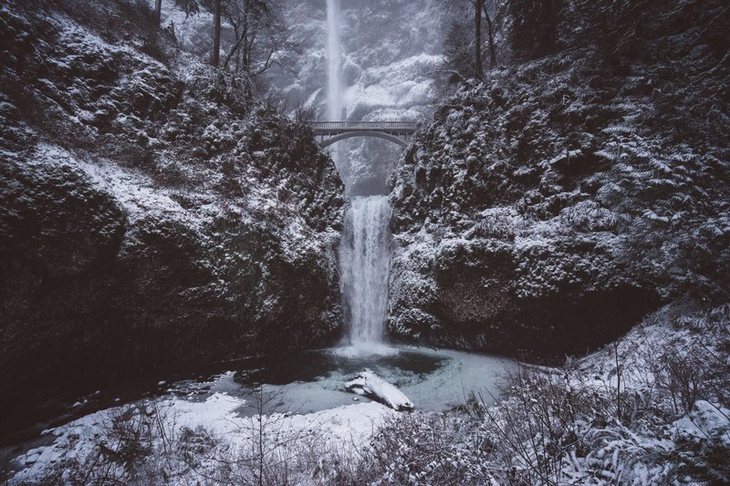 a man wearing a spring jacket jogging on the side of the road near multnomah falls, white multnomah falls 4k
