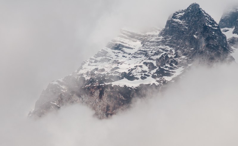 a snowy mountain partially obscured by a thick mist, a king in a bed of clouds 4k