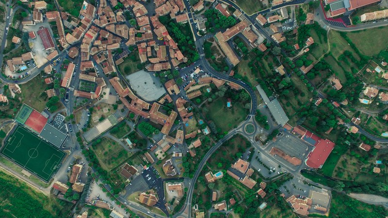 drone aerial view of the les vans village houses streets a roundabout and a soccer field, drone aerial view of les vans 4k