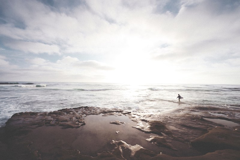 surfer walking into the rough ocean at sunset in san diego, surfer walking into the ocean 4k