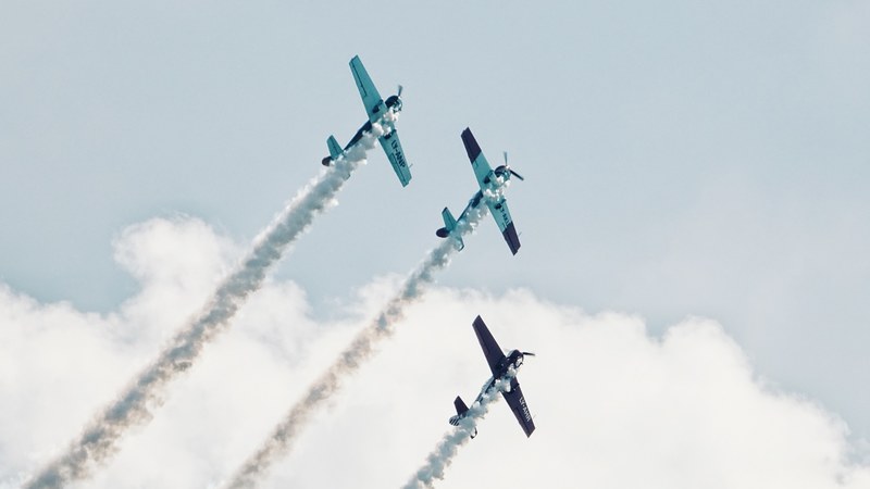 three small planes leaving white smoke trails behind at an air show, three planes at an air show 4k