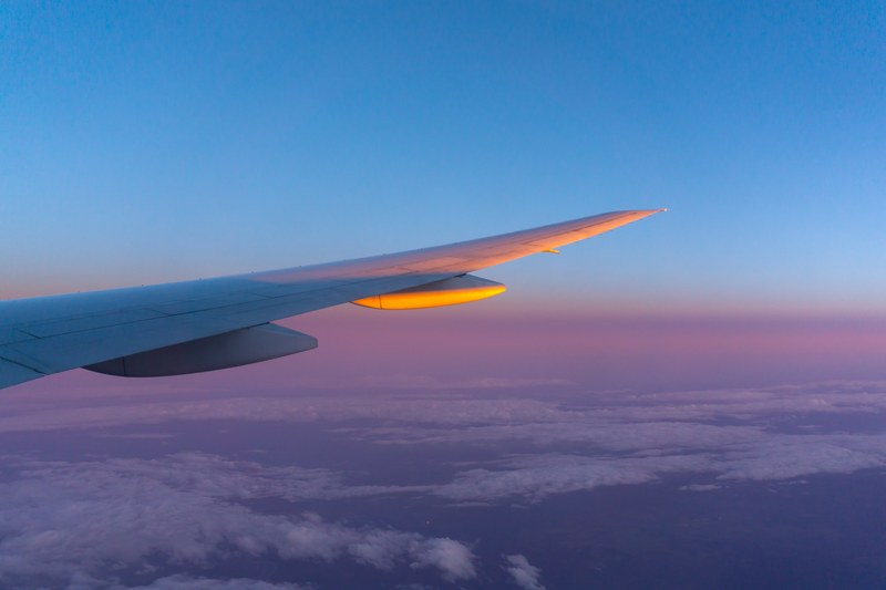 the airplane wing and cloudy plains below seen through an airplane window, airplane over cloudy plains 4k