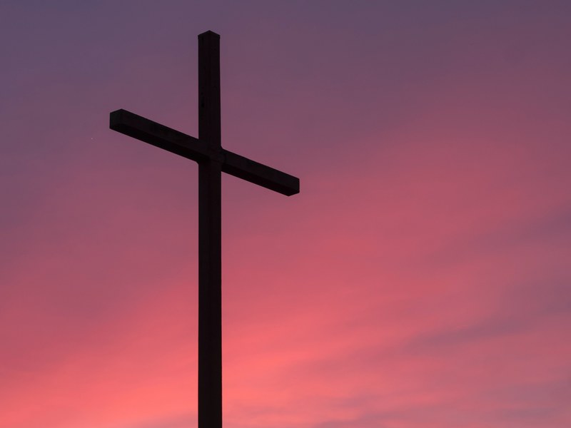 a cross against a pink and purple sky, cross during sunset 4k
