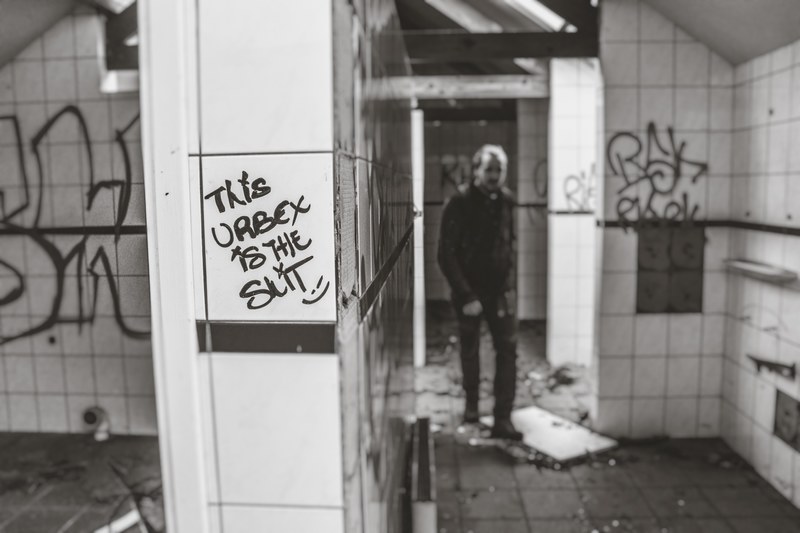 black and white shot of person in decaying bathroom with graffiti on walls in doel, doel belgium_ 4k