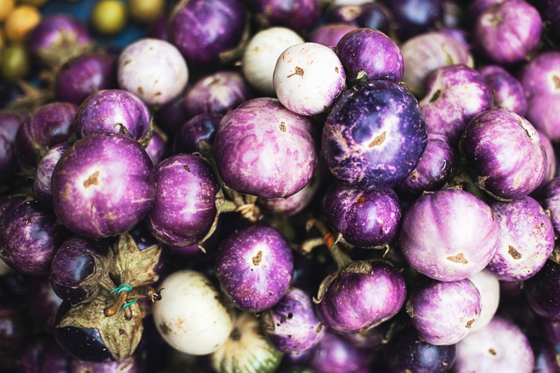 stack of purple eggplant seeds at a vegetable stand, veggies for sale 4k