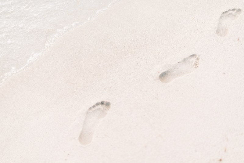 a close up of footprints left by a person walking barefoot on a sandy beach, beach footprints 4k