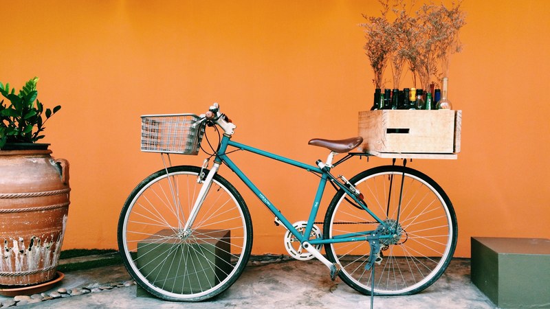 a bicycle with a crate of wine on its carrier against an orange wall, old bicycle meets designer 4k
