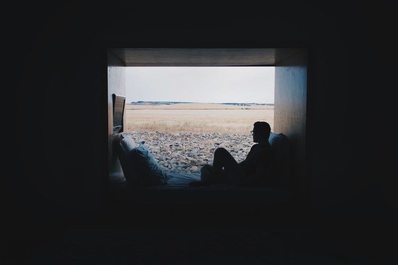 man with glasses relaxing near window on sofa with rocky ground outside aire de bardenas, man relaxing near window 4k
