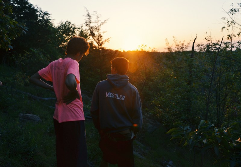two guys standing next to each other talking during golden hour in the forest, guy friends 4k