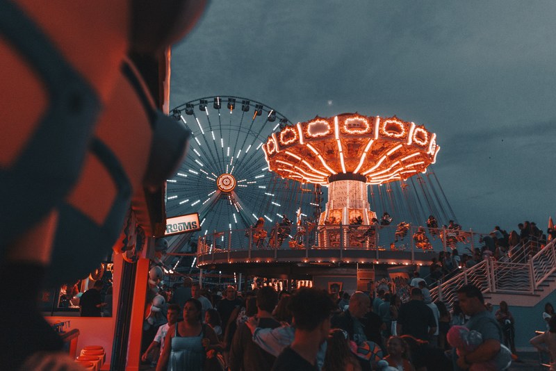crowd enjoying wildwood boardwalk amusement park with swing ride and ferris wheel glowing in the night, round round part 5 4k
