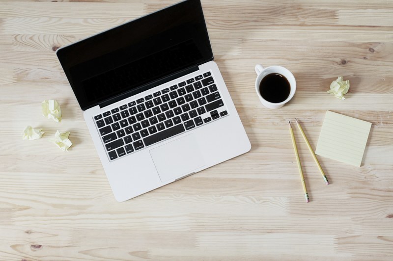 an overhead shot of a cup of coffee next to an open laptop two pencils and a stack of sticky notes, taking notes at coffee time 4k