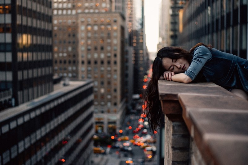woman with long hair sleeping on the brick balcony edge among skyscrapers in new york, woman sleeping on new york balcony 4k