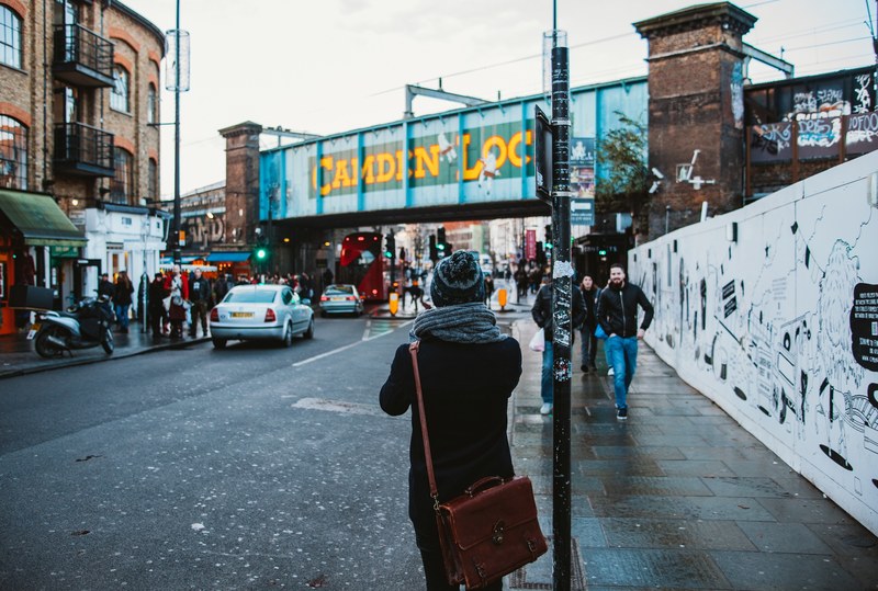 a person in a knit cap and a scarf standing on a sidewalk on a rainy day in camden lock, camden lock street view 4k