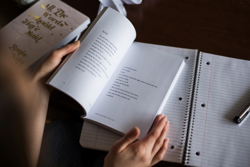 person reading a book of poems and taking notes, young person reads poetry book 4k