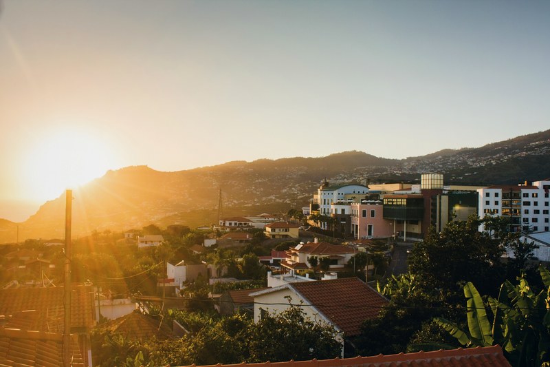 the sunrise or sunset over city rooftop building tree and hillside on madeira island, madeira island rooftop at sunrise or sunset 4k