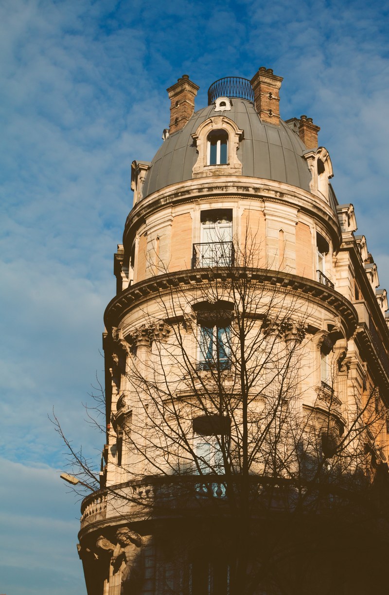rounded corner of a house with windows with blue and partly cloudy skies, building with windows 4k