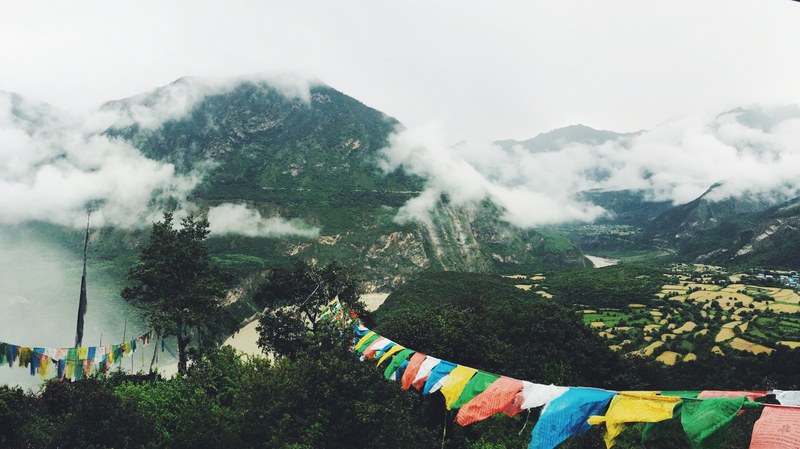 colorful bunting hanging between treetops with view on a cloud shrouded mountain, bunting in the mountains 4k