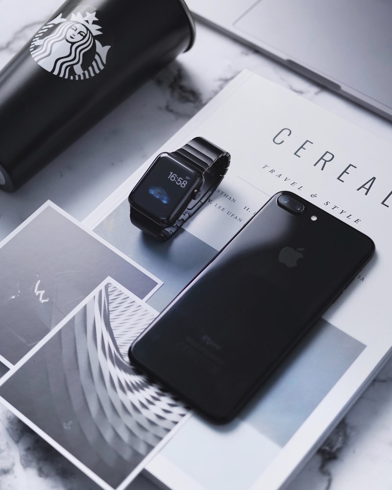 iphone apple watch and black starbucks cup on top of cereal magazine, minimalistic flatlays 4k