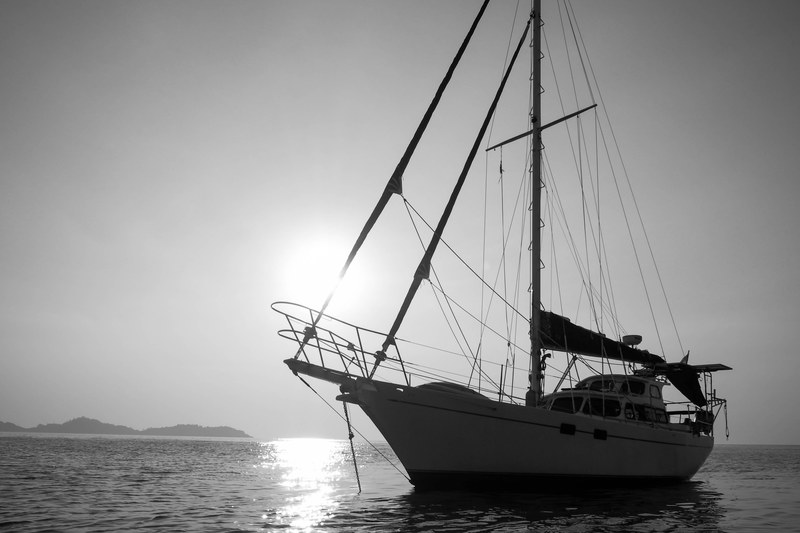 black and white shot of yacht on sea with clear sky and sun in background, monochrome yacht and sun 4k