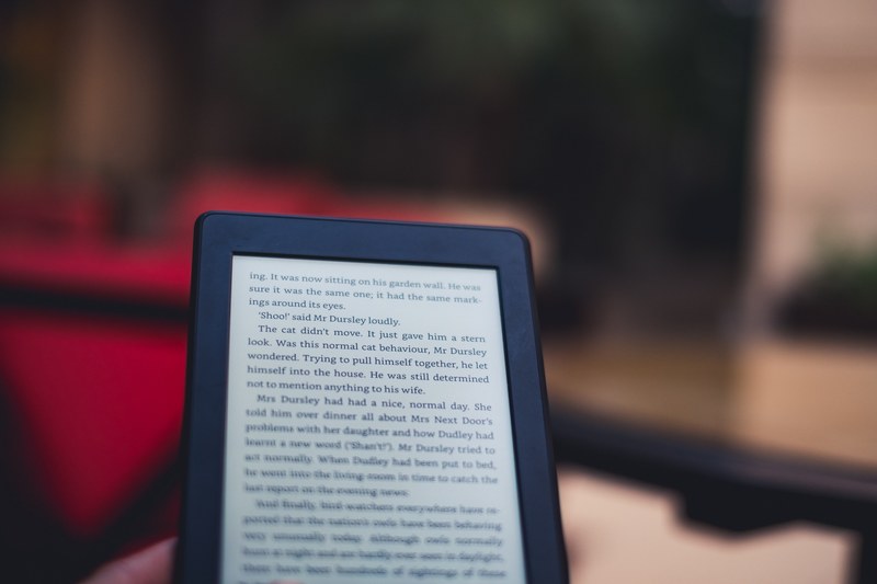 macro of kindle electronic reader displaying the text of a book with a blurry background, reading harry potter 4k
