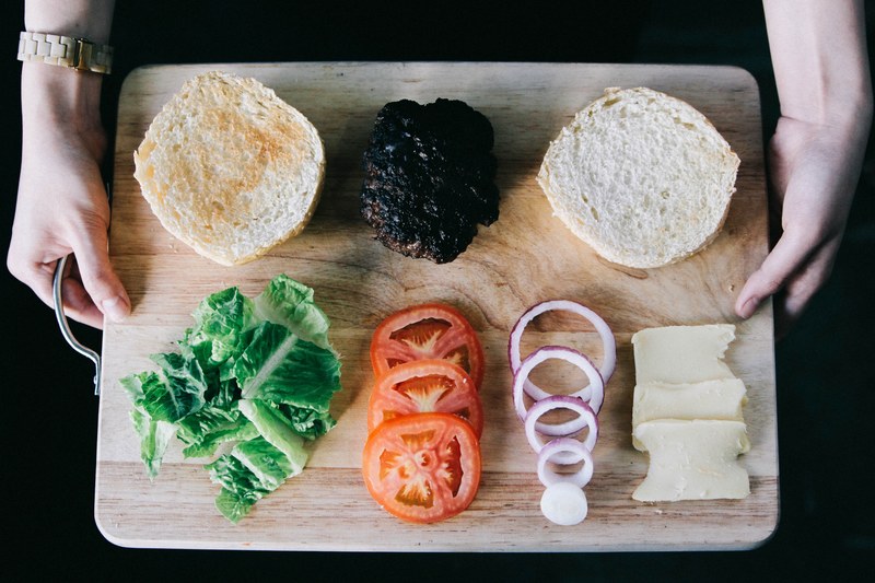 neatly organized cutting board with hamburger cheese and vegetable fixings, burger fixings 4k