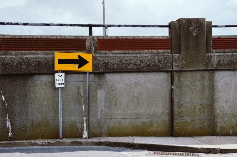 a no left turn sign next to a concrete ledge at the side of a road, no left turn 4k