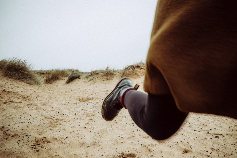 view of one leg in boots while running on the sand, one leg in boots while running 4k