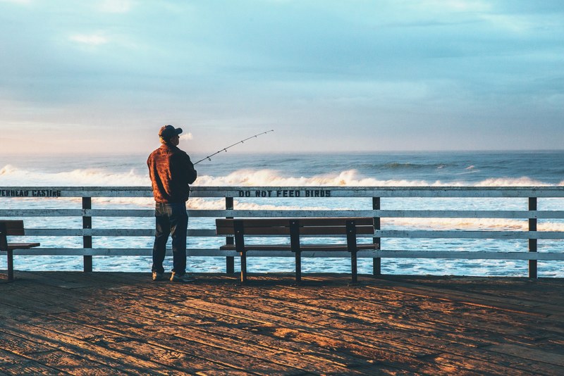fisherman fishing at the wooden pismo beach pier, do not feed birds 4k