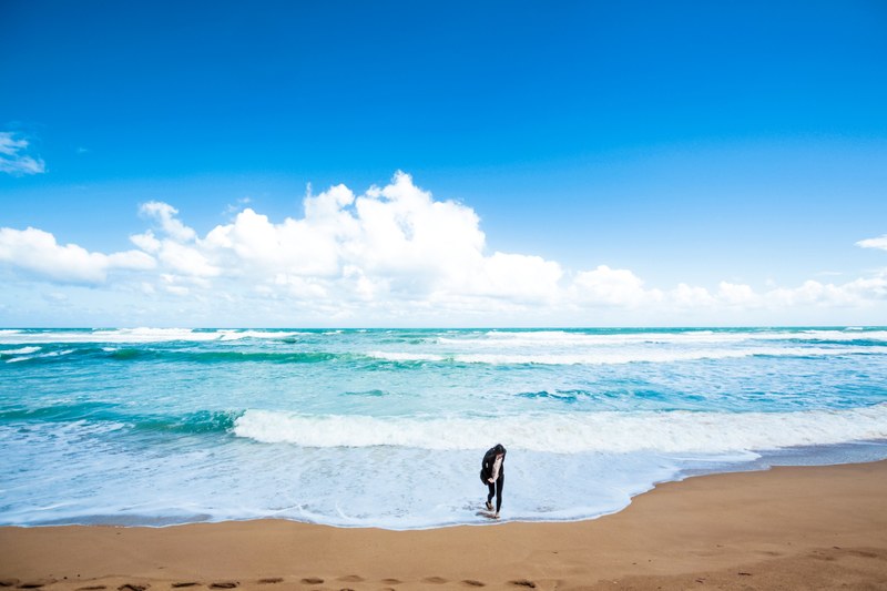 woman on the sand beach while ocean waves are washing ashore at twelve apostles, onto the beach 4k
