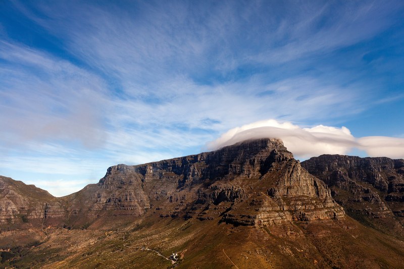 a large flat mountain with large fluffy clouds hovering above, clouds over a flat mountain 4k
