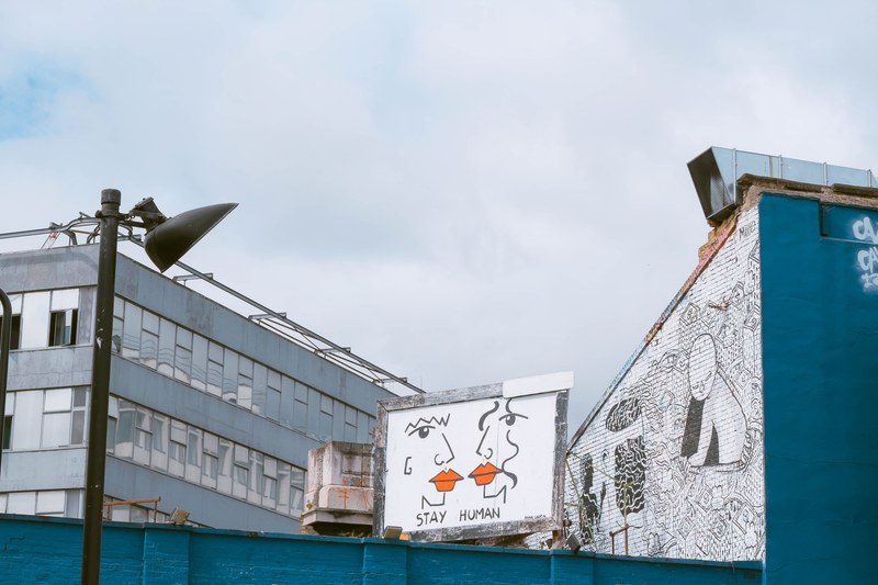 stay human graffiti artwork on billboard in shoreditch near buildings with cloudy sky, pushing the human race forward 4k