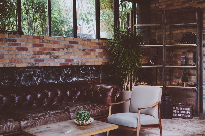 a living room with brick walls a leather quilted sofa steel bookshelf plants and coffee table in istanbul, take a seat 4k