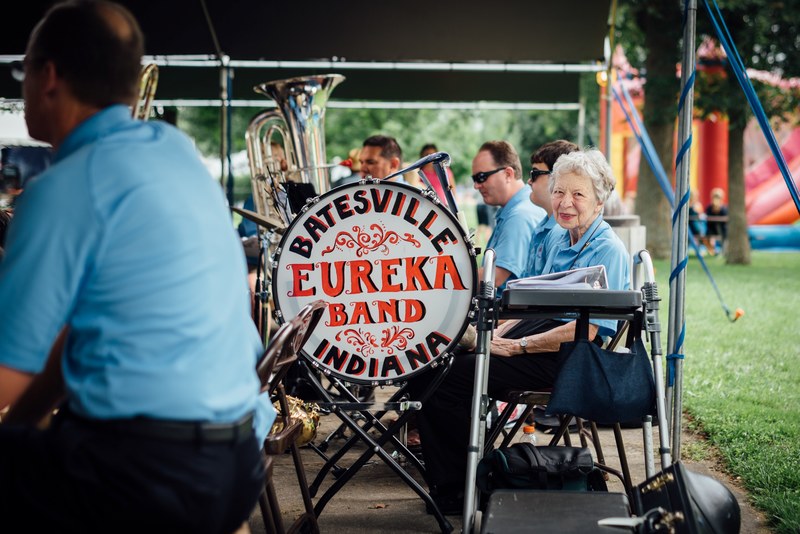an elderly woman smiles into the camera during the performance of a concert band, batesville concert band during performance 4k