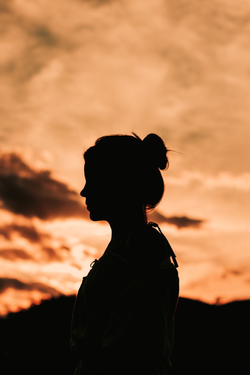 silhouette of a woman standing alone under an orangesunset, silhouette_ 4k