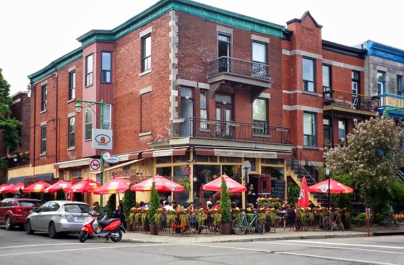 people sitting at tables on a restaurant patio at the corner of a building, restaurant patio 4k