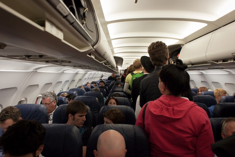 the inside of a plane with people standing in the aisle to take their seats, before take off 4k