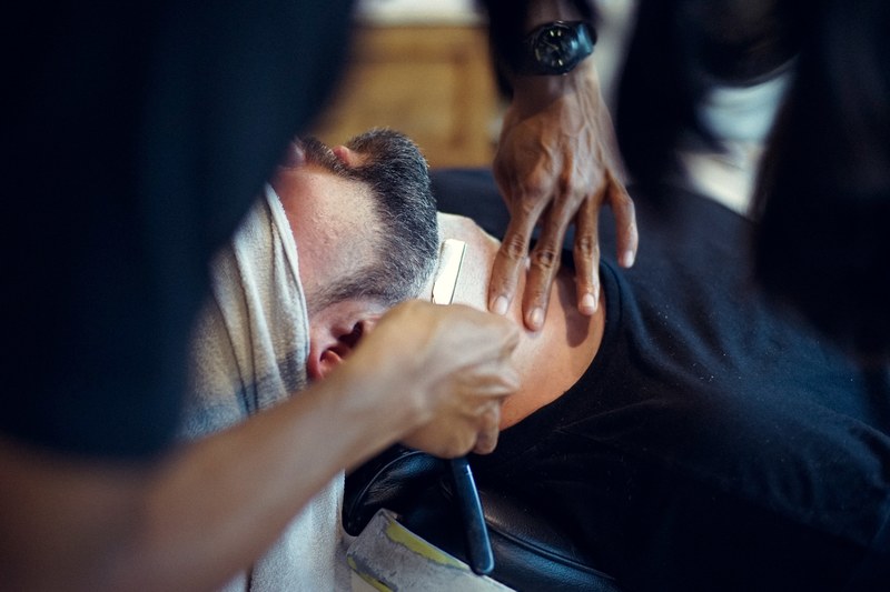a bearded man gets a shave on his throat at a barbershop, man getting a shave 4k