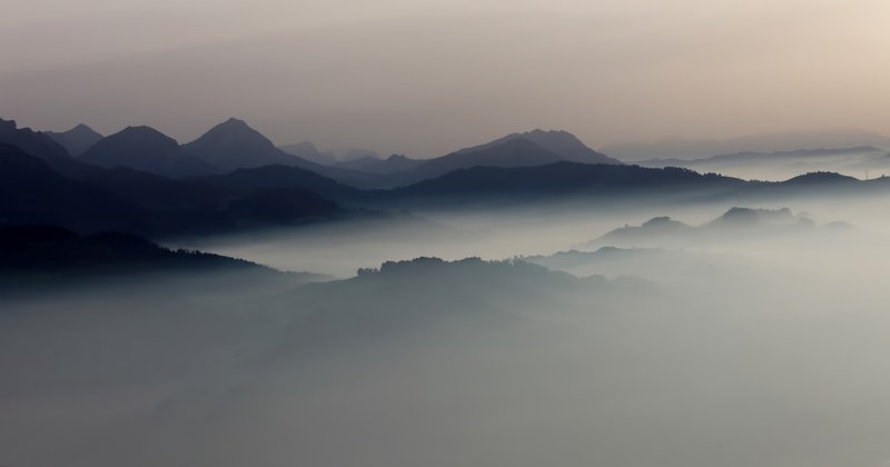 dark silhouettes of mountain peaks emerge from the mist in lucerne, balloon view 4k