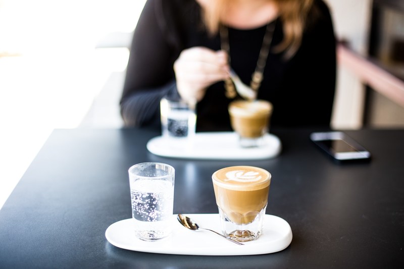 a woman sitting over a cup of coffee with another cup of coffee on the other side of the table, going out for a coffee 4k