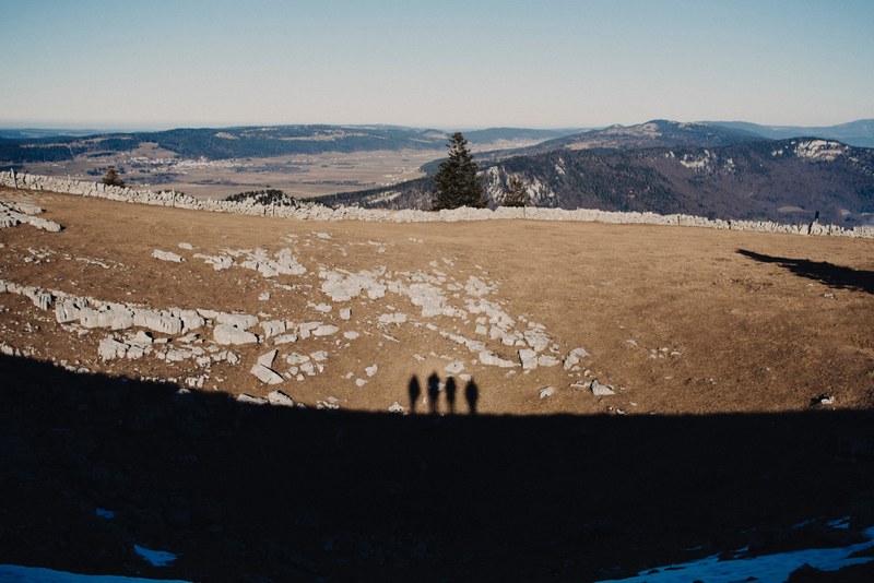 shadows of four people standing on elevated terrain on a rocky plain the mountains, expedition 4k